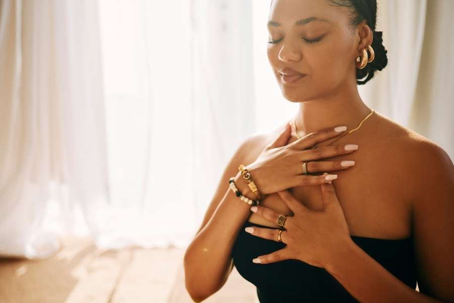 Une femme en méditation avec les mains sur le cœur pour la méditation intégrée au yoga.
